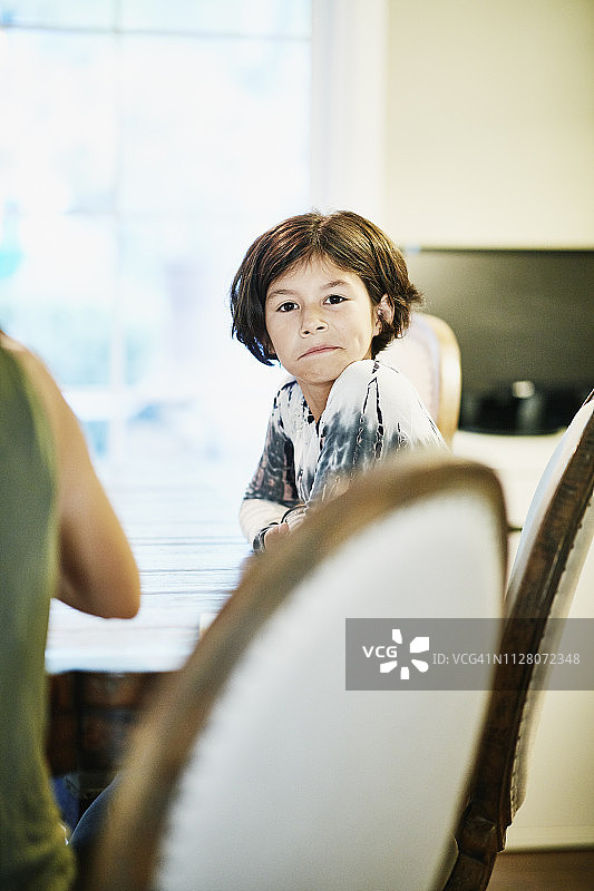 年轻女孩在餐厅餐桌旁做鬼脸的肖像图片素材