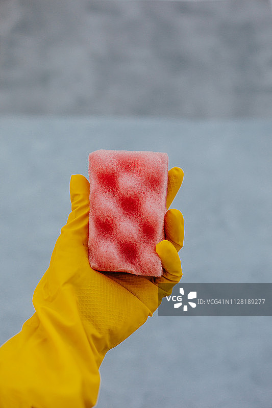 手持黄色橡胶手套和清洁刷图片素材