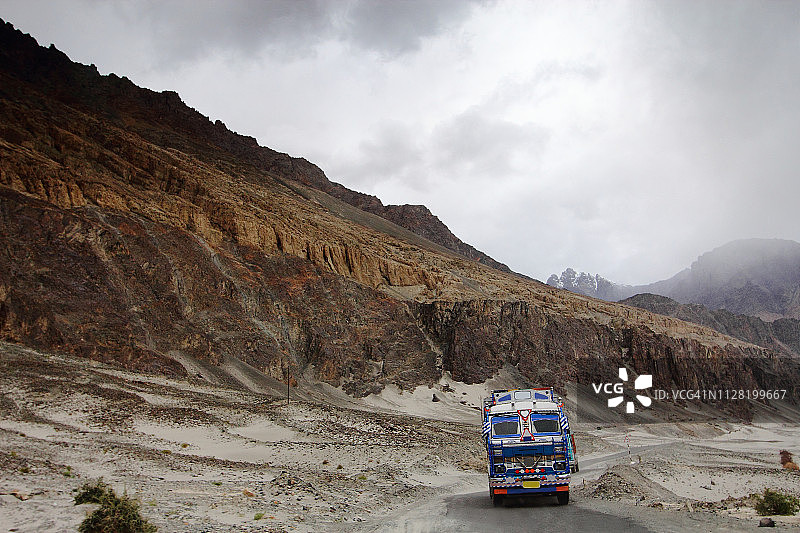 阴天，印度大卡车行驶在狭窄的山路上图片素材
