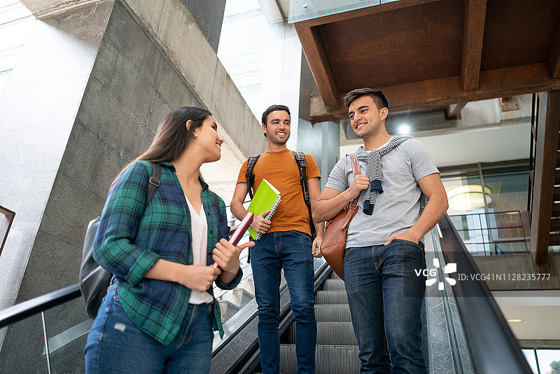一群朋友在大学校园乘坐自动扶梯下课后离开图片素材