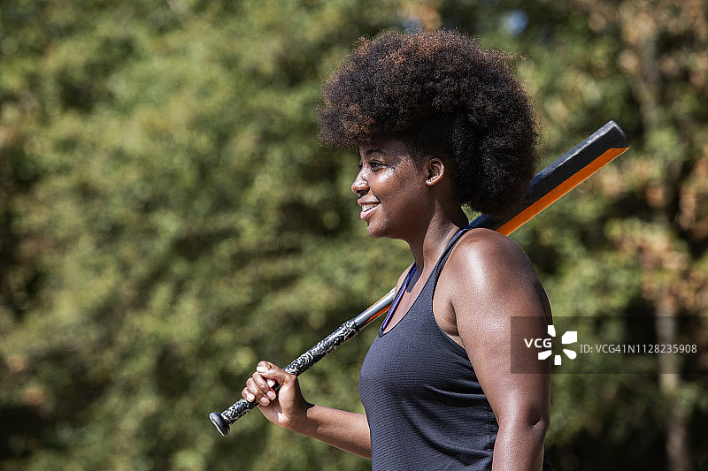 击球的年轻卷发女垒球员图片素材