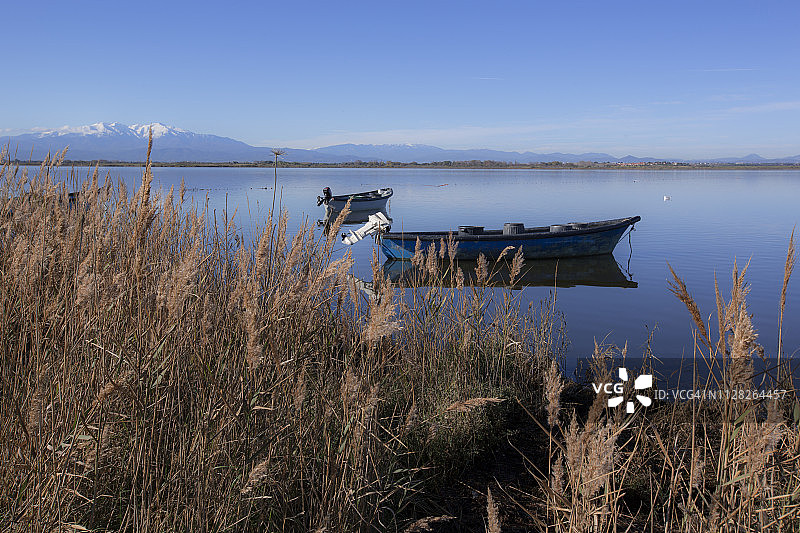 两艘渔船在平静的湖面上，远山背景图片素材