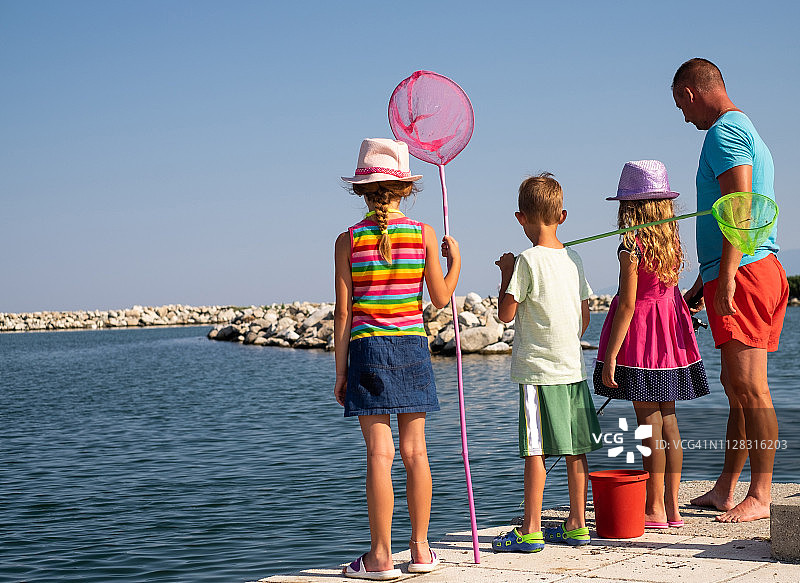一家人在港口钓鱼的后视图图片素材