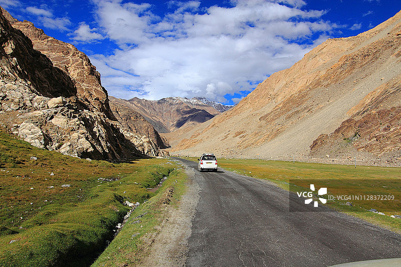 汽车行驶在棕色群山环绕的道路上图片素材