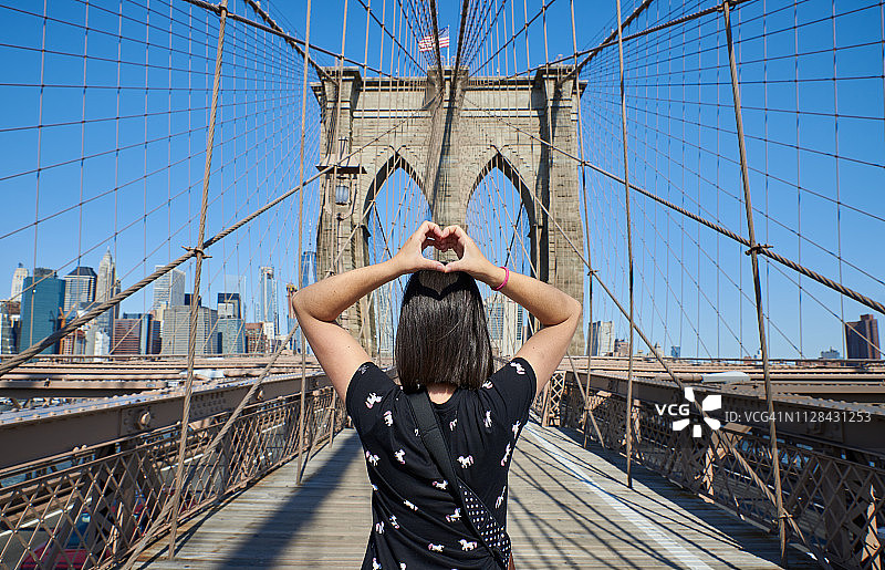 在布鲁克林大桥上仰望纽约城市景观的年轻女子图片素材