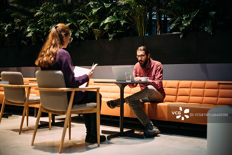 一位女商人与一位男商人在共享办公场所面对面坐着图片素材