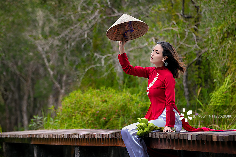 身穿越南传统奥黛的女子在森林中采莲图片素材