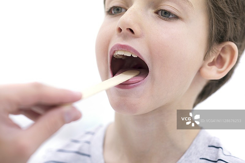 张着嘴巴，用压舌板的男孩图片素材