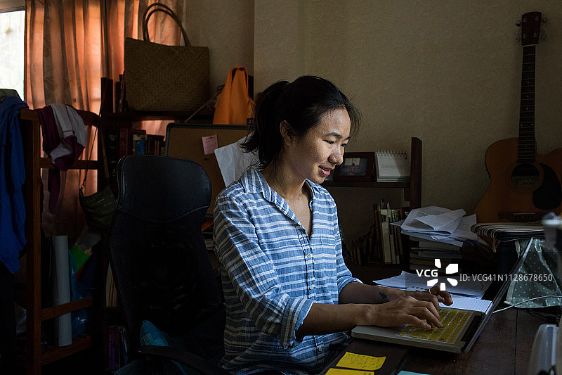 在家里用笔记本电脑工作的泰国女社会工作者图片素材