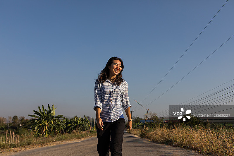 走在乡村街道上的快乐亚洲女性图片素材