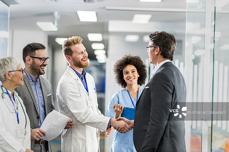 快乐的医生与商人在医院达成协议图片素材