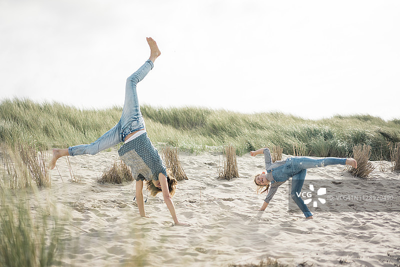 母女在沙滩上快乐地玩耍，翻筋斗图片素材
