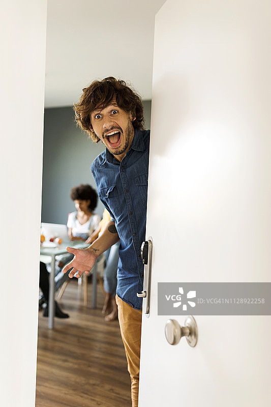 朋友在背景中开门的惊讶男人的人物肖像图片素材