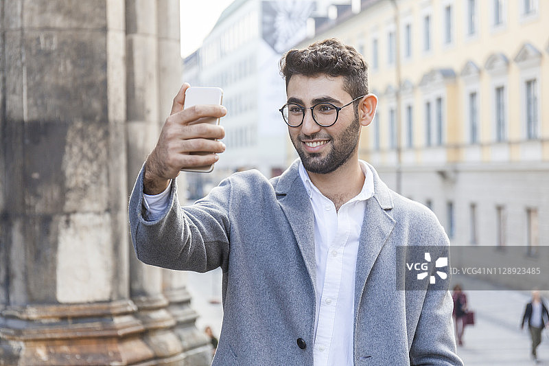 德国慕尼黑：年轻商人用手机在城市自拍图片素材