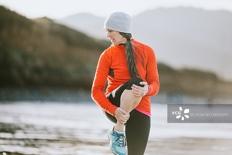 中年妇女在海滩伸展运动图片素材