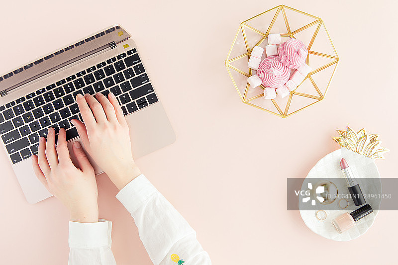 粉色背景工作区：笔记本电脑与女人手图片素材
