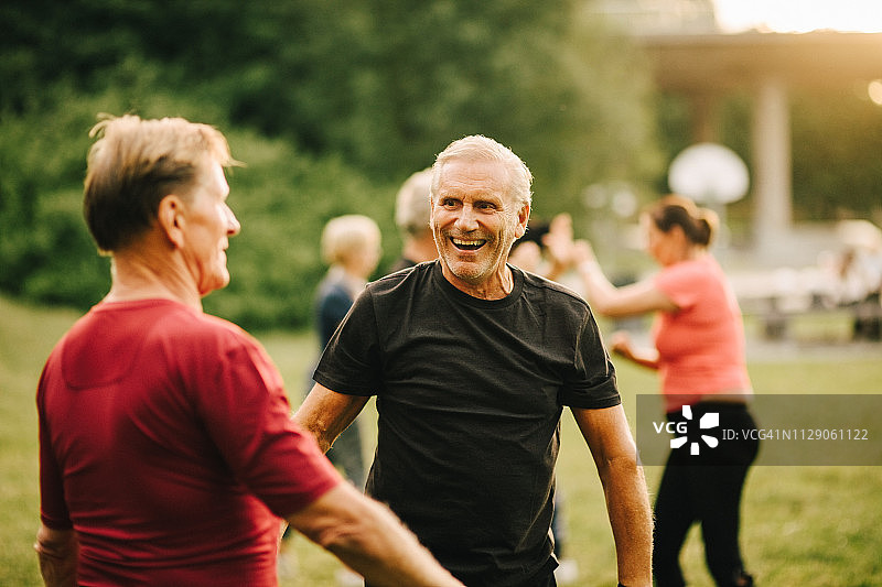 在公园里，朋友在后台练习拳击，年长的男性笑着图片素材