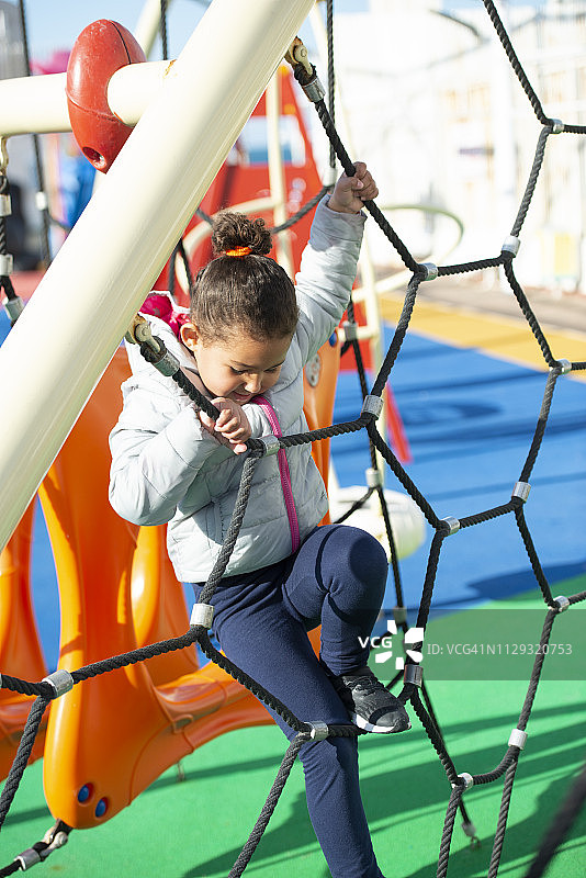 女孩在操场绳索上攀爬图片素材