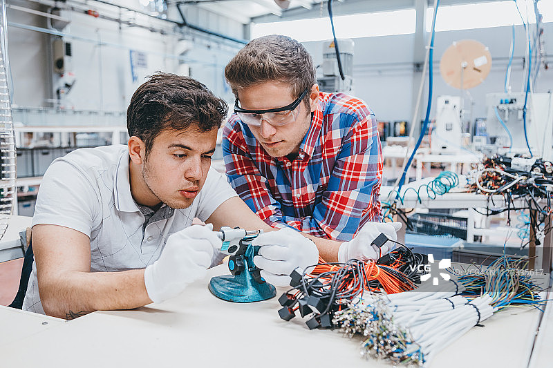 在生产设备旁工作的年轻产业工人图片素材