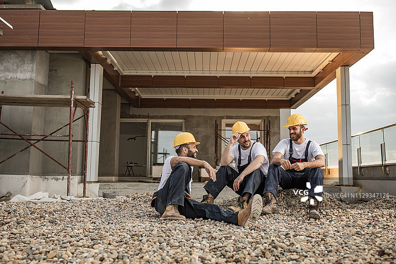 快乐的建筑工人在阳台上放松交谈图片素材