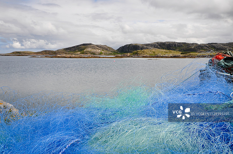 聚焦：码头上铺设的蓝色渔网，以海景为背景。图片素材