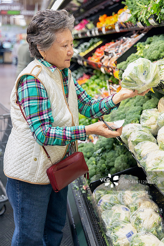年长的女人在杂货店精心挑选农产品图片素材