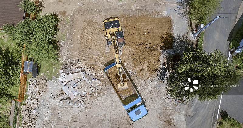 挖掘机在建筑工地将挖出的土壤装载到卡车上图片素材