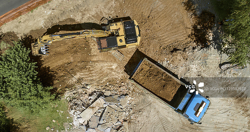 挖掘机在建筑工地将挖出的土壤装载到卡车上图片素材