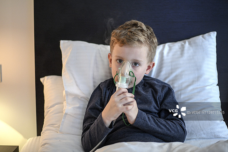 接受吸入治疗时使用雾化器的小男孩图片素材