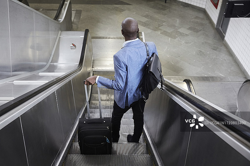 商务人士在地铁站自动扶梯上携带行李的高角度后视图图片素材