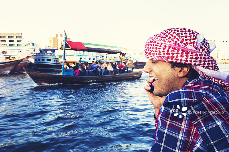 年轻游客在迪拜河的船上打电话图片素材