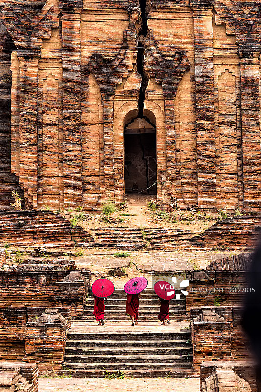 在敏贡佛塔上行走并撑着红色雨伞的三个小沙弥，缅甸曼德勒，蒲甘图片素材