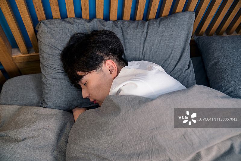 在床上睡觉的年轻亚洲男子图片素材