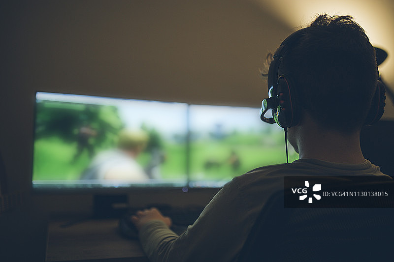 小男孩在家玩电脑游戏图片素材