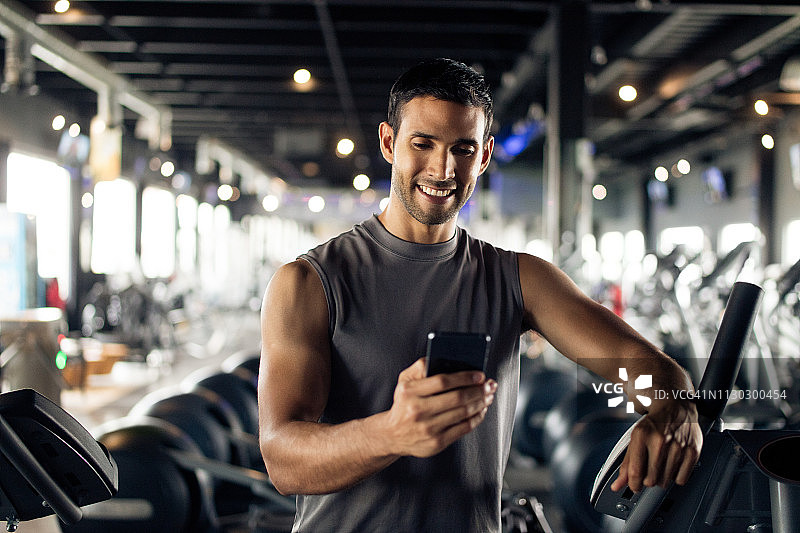 在健身房发短信的拉丁裔男人图片素材