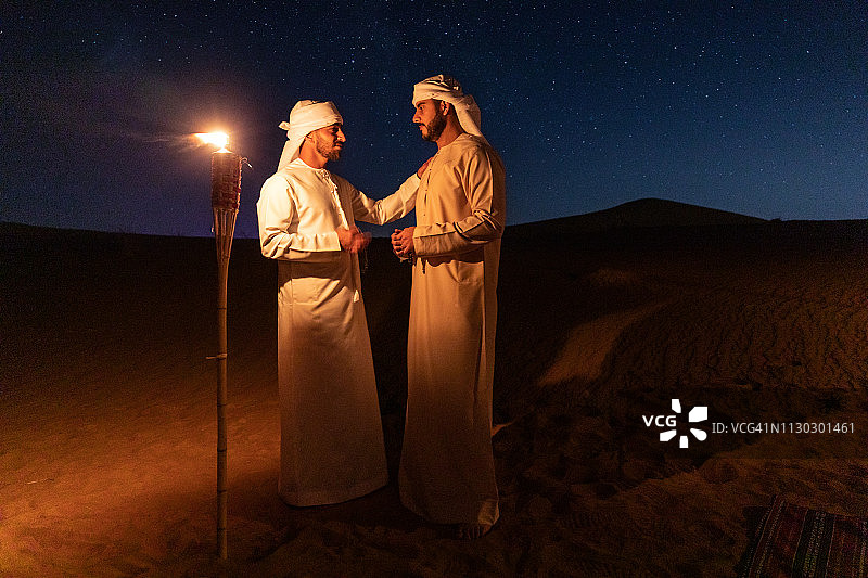夜晚沙漠中身着传统服饰的阿拉伯人图片素材