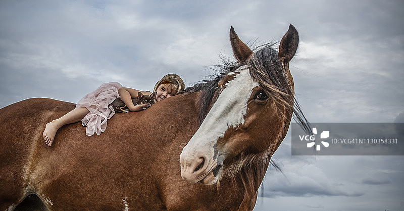 小女孩躺在巨大的克莱兹代尔马身上图片素材