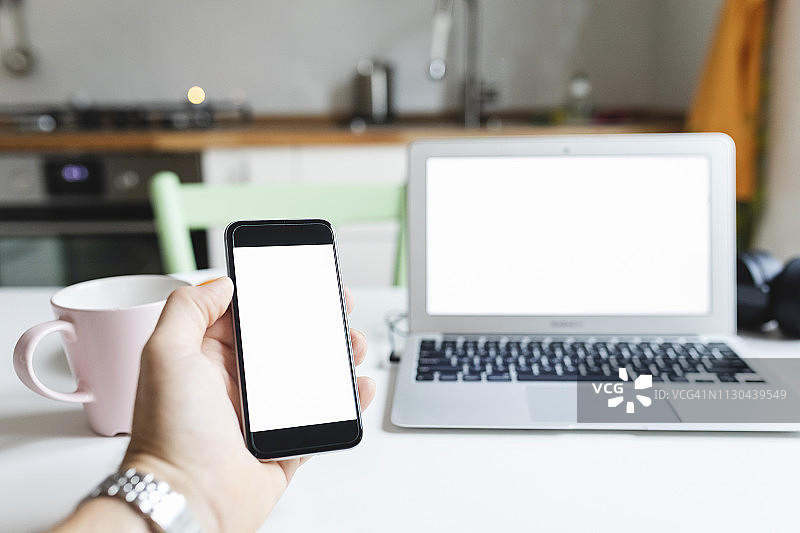 厨房桌上的智能手机和笔记本电脑图片素材