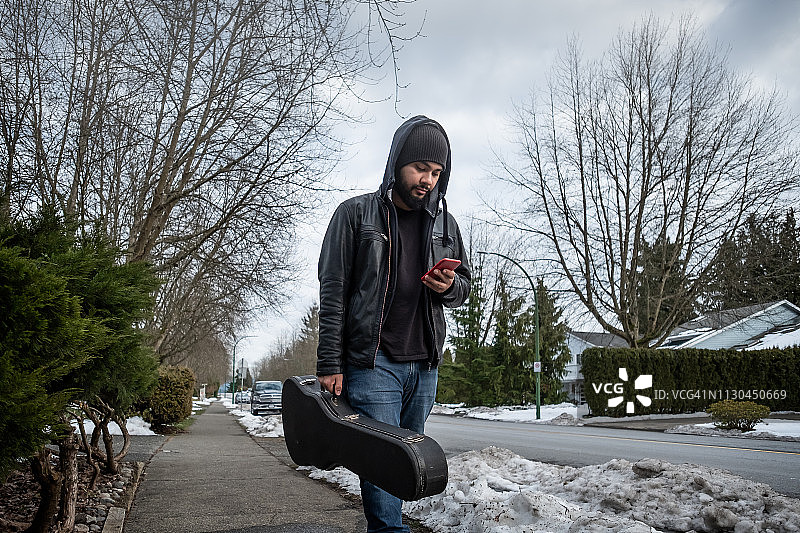 在雪街上抱着吉他行走图片素材