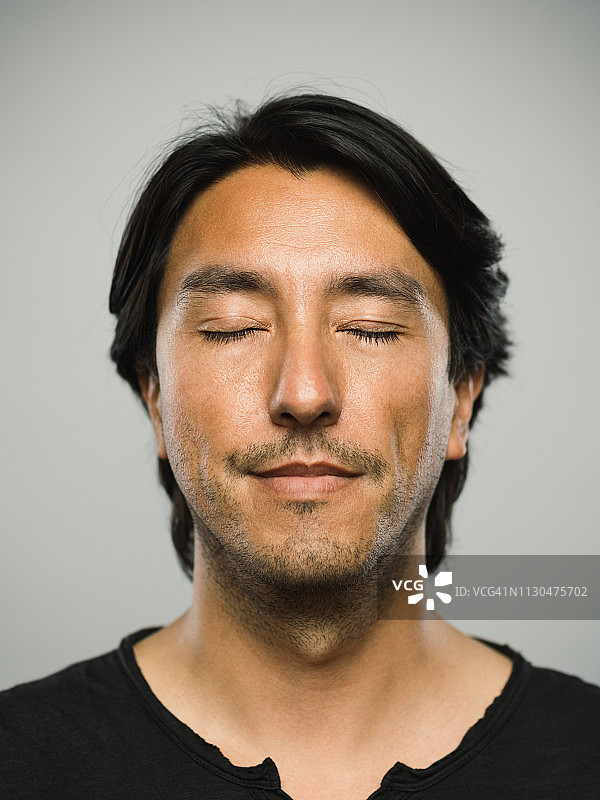 面无表情、闭着眼睛的西班牙裔男子肖像图片素材