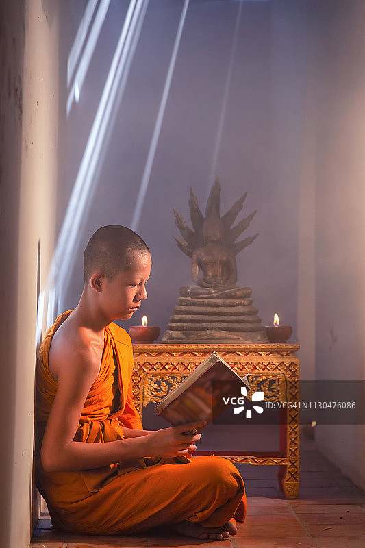 年轻的见习僧侣在寺庙里诵读佛经图片素材