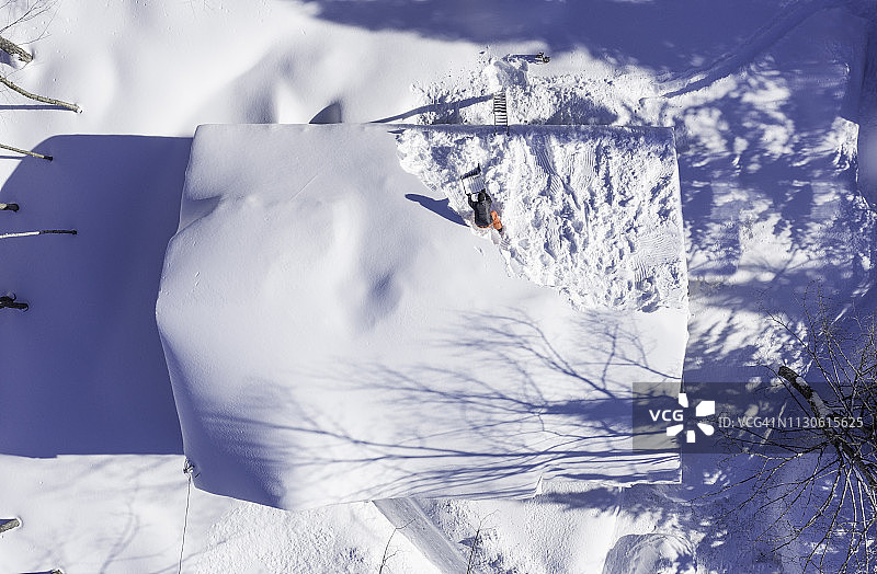 暴风雪过后，一人在屋顶铲雪的鸟瞰图图片素材