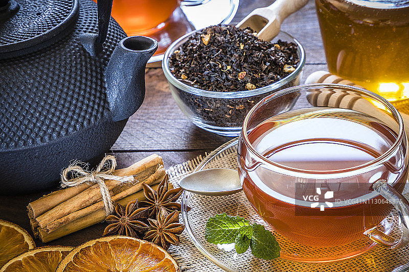 下午茶：一杯茶、肉桂棒、茴芹、木桌上的干橙图片素材