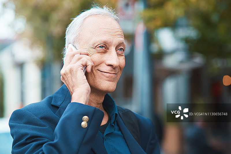 微笑的中年男人在街上用手机听音乐图片素材