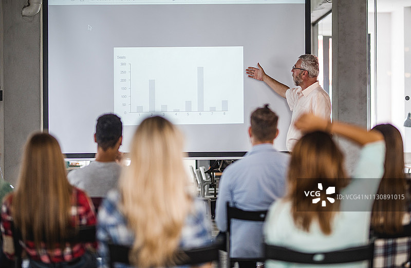 资深教师在教室里给大学生们做讲座图片素材