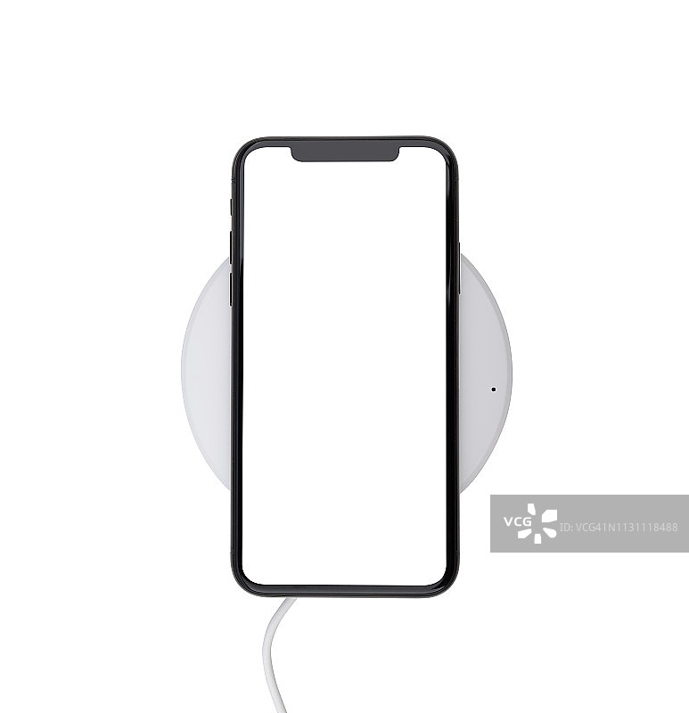 现代智能手机在无线充电器上进行无线充电，隔离在白色背景上图片素材