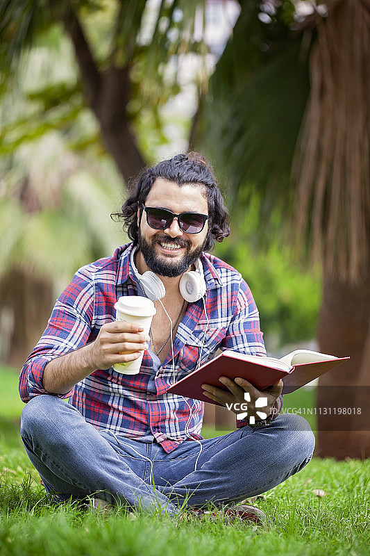 在公园里看书的年轻潮人正面图图片素材