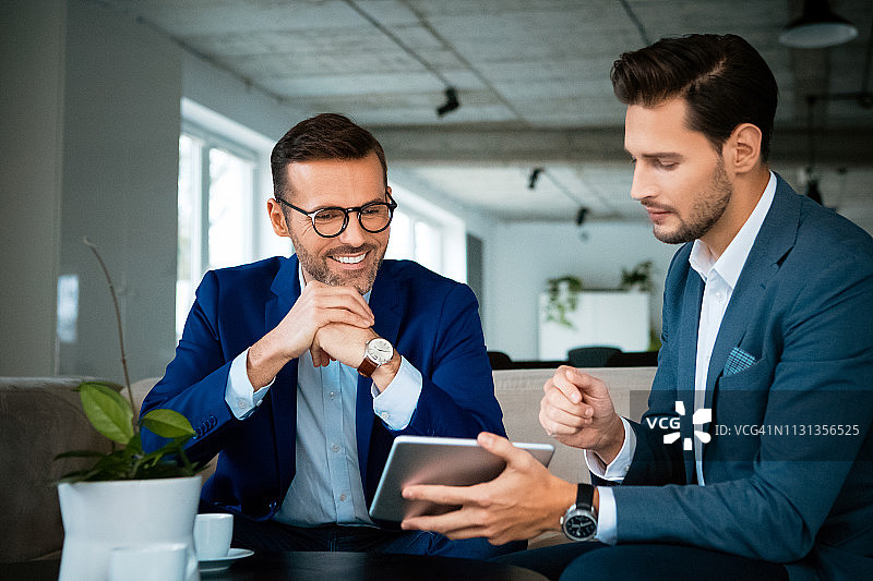 微笑的同事在平板电脑上讨论图片素材