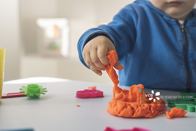 女婴玩橡皮泥的手部特写图片素材