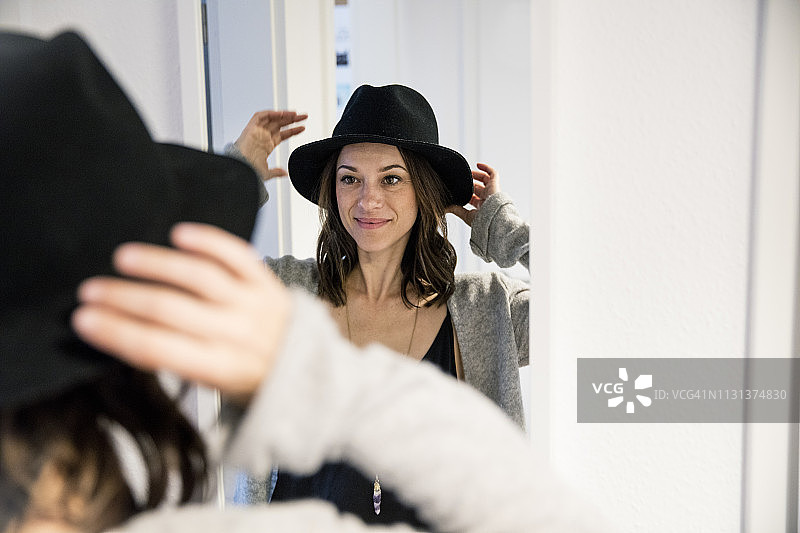 站在镜子前戴帽子的中年妇女图片素材